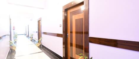 Un pasillo con una puerta de madera con el número 109, plantas en macetas y un cubo rojo.