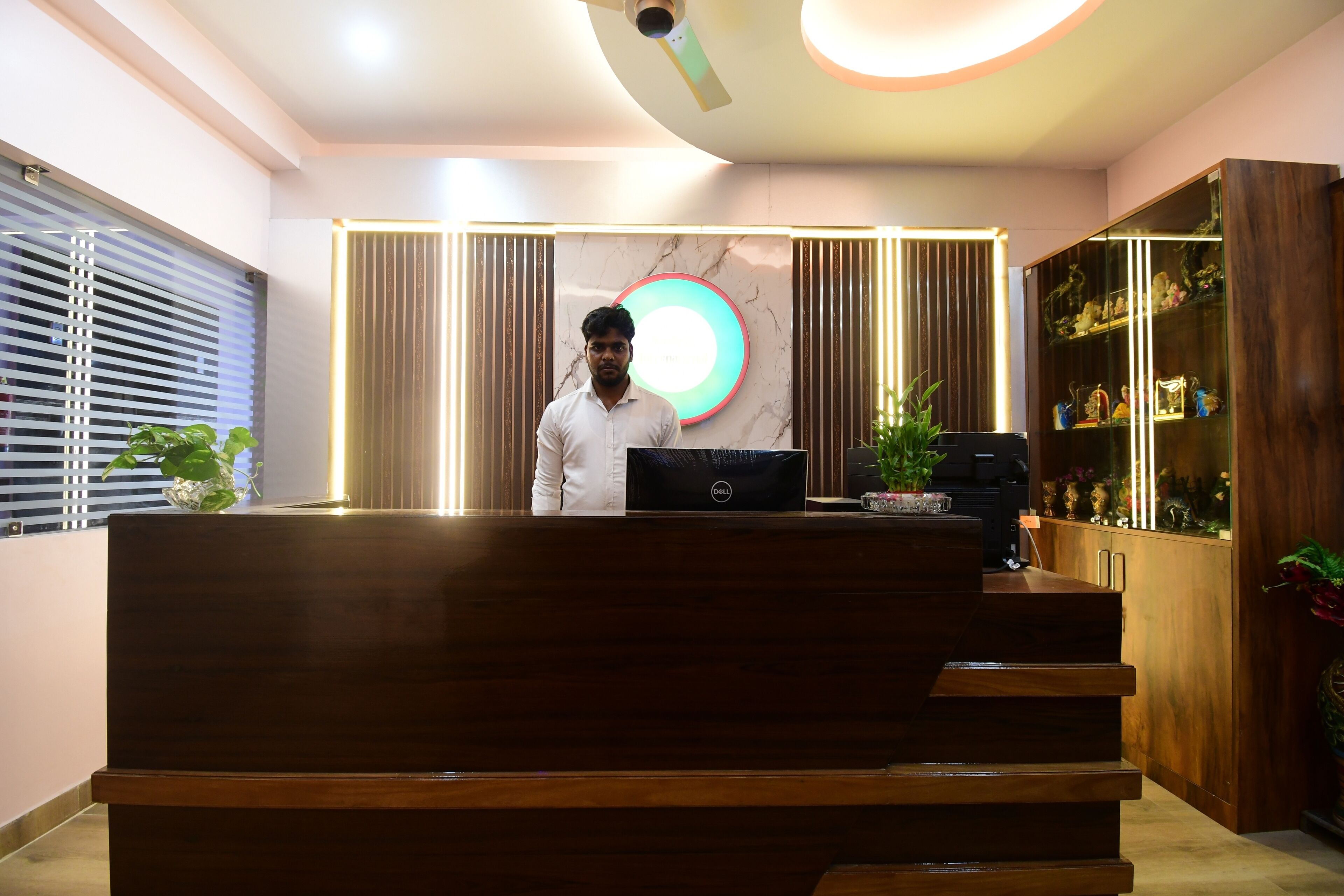 A reception desk with a laptop, a ceiling fan, and a decorative light fixture.
