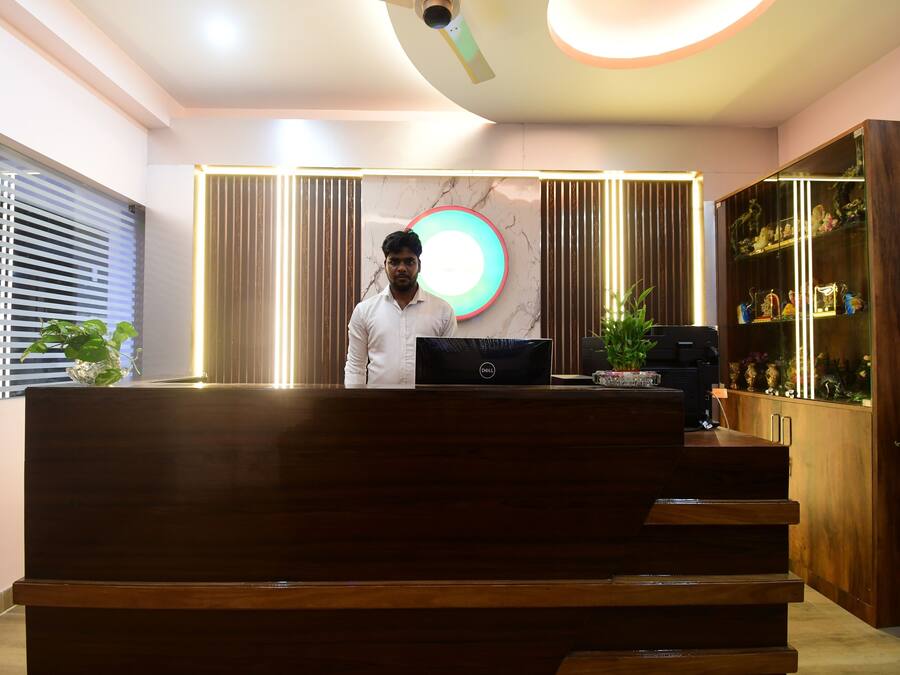 A reception desk with a laptop, a ceiling fan, and a decorative light fixture.
