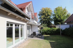 A residential building with a balcony, a patio with outdoor furniture, and a well-maintained lawn.