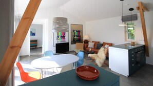 A modern living space with a dining area, kitchen, and seating area. - Freistehender Bungalow in der Künstlerkolonie Ahrenshoop (Ostseebad Ahrenshoop)
