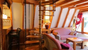A cozy room with a spiral staircase, wooden furniture, and a view of the outdoors.