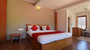 Een slaapkamer met een houten bed, een klein houten bankje en uitzicht op een stadsgezicht door een raam.