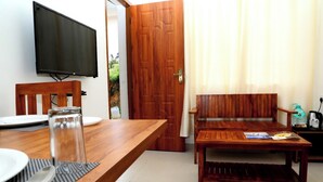Een eetgedeelte met een houten tafel, stoelen, een televisie en een bank.