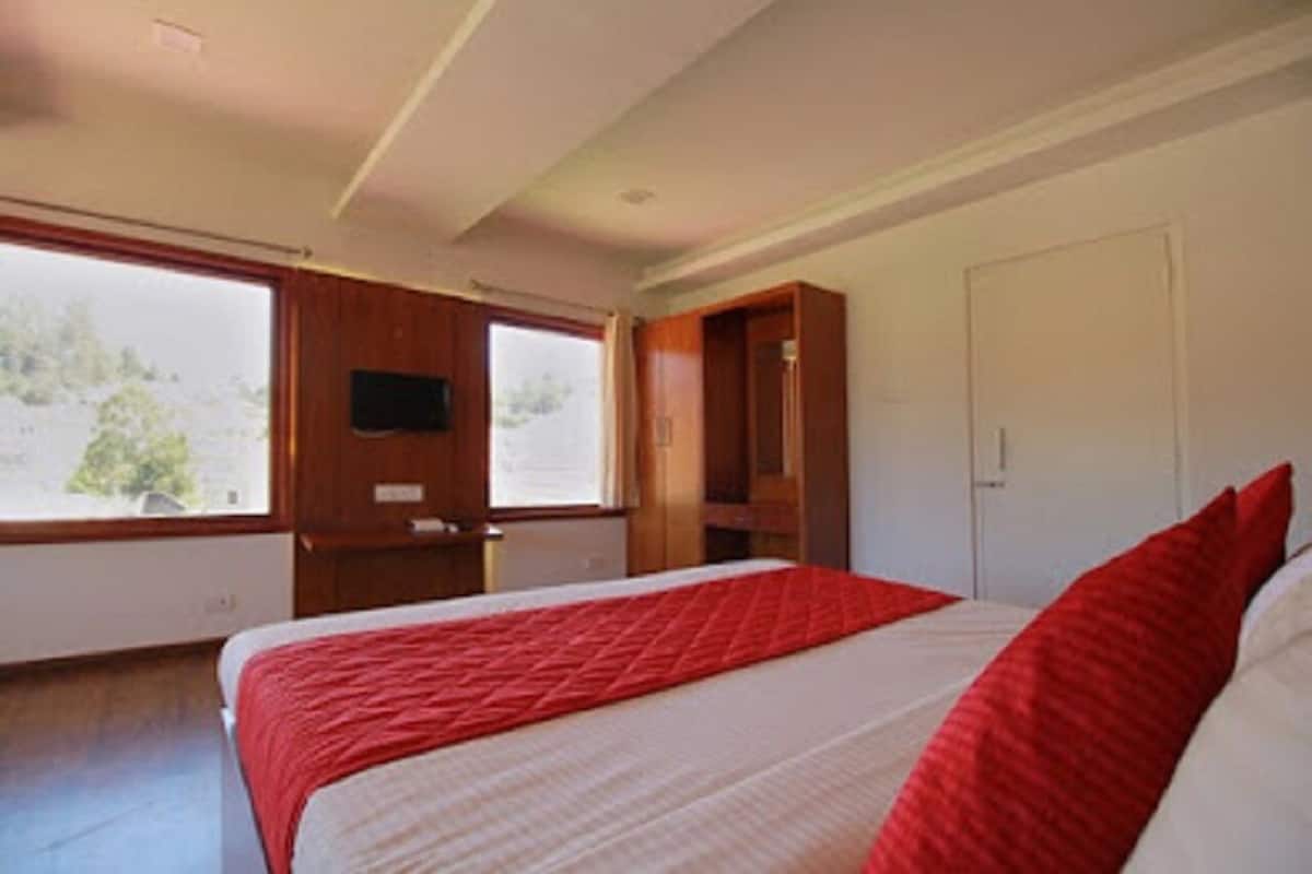 Een slaapkamer met een bed, een televisie aan de muur en een raam.