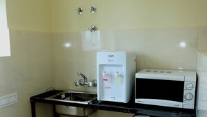 Een kleine keuken met een spoelbak, een magnetron en een tafeltje.