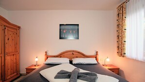Uma cama bem arrumada com uma toalha, duas luminárias de cabeceira e um quadro na parede.