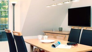 Una sala de reuniones moderna con una mesa larga, dos sillas, un televisor de pantalla plana y un aplique de techo.