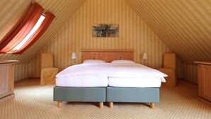 Un dormitorio con una cama grande, dos mesitas de noche, un cabecero y una ventana con cortinas.