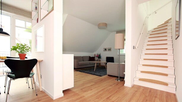 A modern living space with a staircase, a dining area, and a cozy seating area.