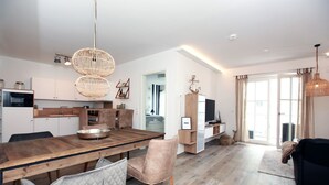 A modern kitchen with wooden cabinets, a dining table with chairs, and pendant lights. - In Unmittelbarer Strandnähe ca. 100m (Ostseebad Wustrow)