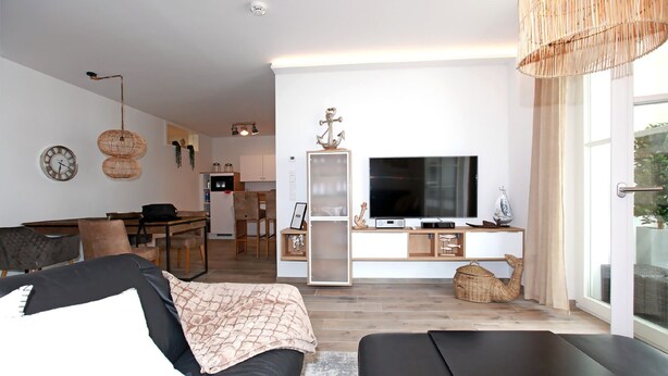 A modern living room with a sofa, a TV, and a dining area with a table and chairs. - In Unmittelbarer Strandnähe ca. 100m (Ostseebad Wustrow)
