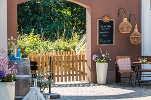 An outdoor seating area with a wooden fence, a chalkboard menu, and two hanging lanterns.