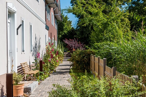 A narrow pathway flanked by a building with a white facade and a wooden fence.
