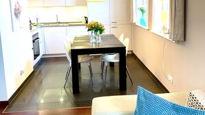 A modern living room with a sofa, a coffee table, and a dining area with a table and chairs. - Haustierfreundlich und in Strandnähe (Ostseebad Wustrow)