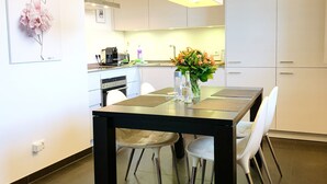 A modern kitchen with white cabinets, a black dining table, and a vase with flowers. - Haustierfreundlich und in Strandnähe (Ostseebad Wustrow)