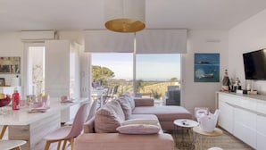 A modern living room with a large window, a sofa, a dining area, and a kitchen. - Les Terrasses d'Azur by Interhome (Sanary sur Mer)
