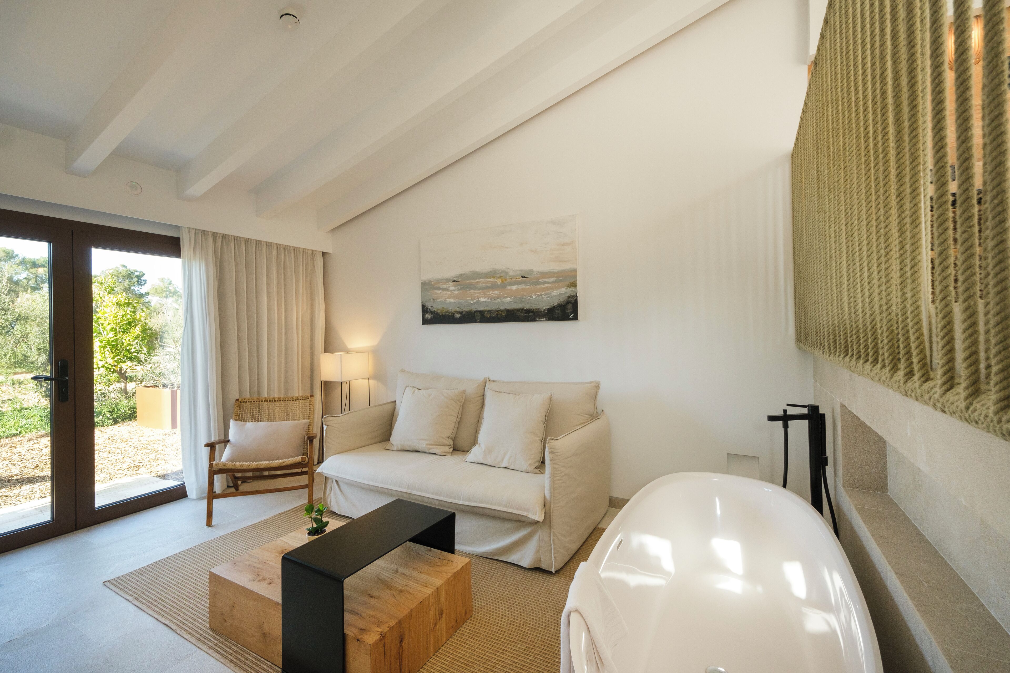 A modern living room with a sofa, a wooden coffee table, a lamp, and a painting on the wall.