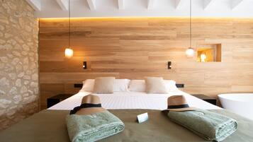 A modern hotel room with a wooden headboard, a large bed with white linens, two bedside tables, and a small window.