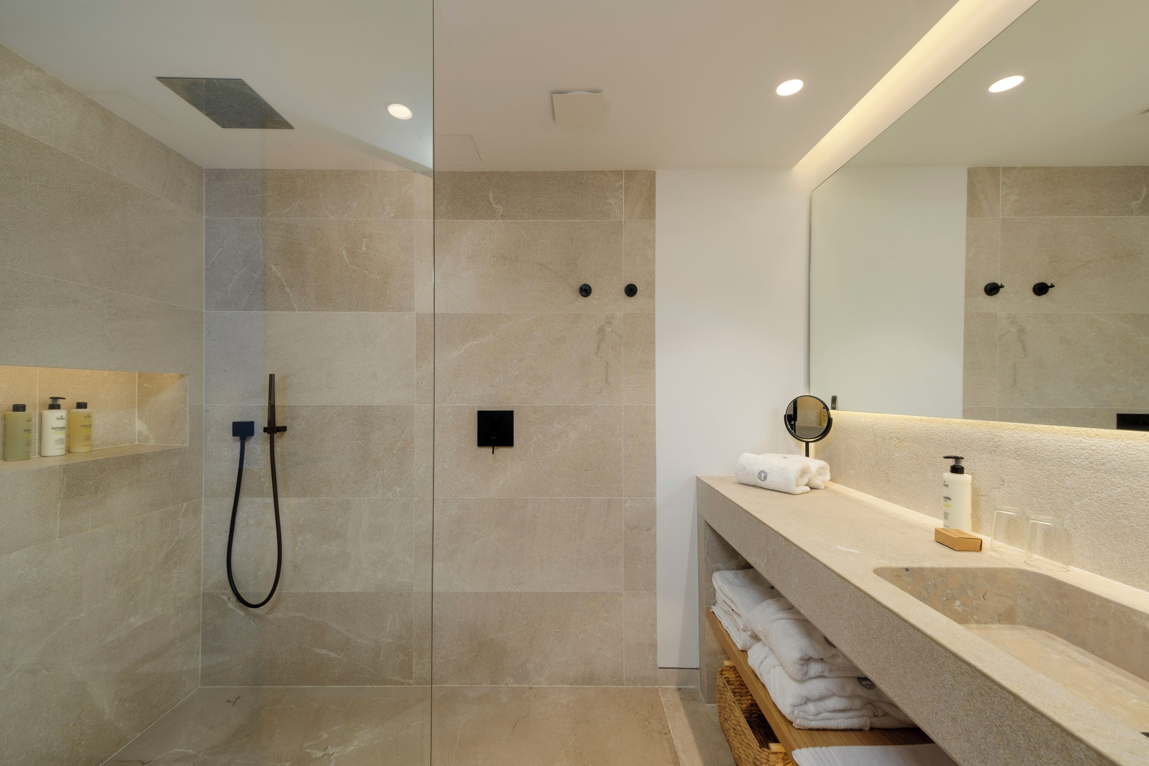 A modern bathroom with a walk-in shower, a large mirror, and a vanity with a sink and towel rack.