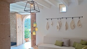 Een moderne woonkamer met een witte bank, groene kussens en een hanglamp.