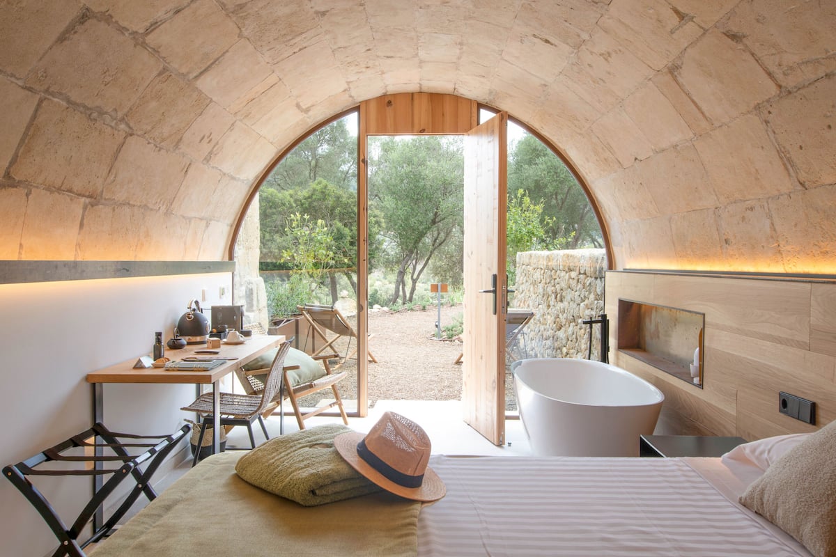 Una habitación acogedora con arco, que incluye una cama, un escritorio y una bañera.