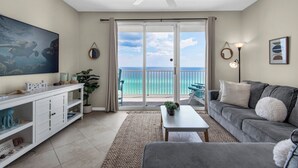 Un salon avec vue sur l’océan, un ventilateur de plafond, un téléviseur et un canapé.