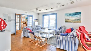 Amplia sala de estar con sofás a rayas, una mesa de centro y una silla roja.