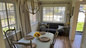 A dining area with a round table, wooden chairs, and a chandelier.