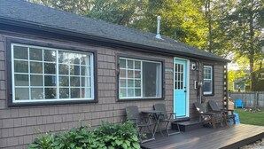 A single-story house with a deck, large windows, and a blue door.