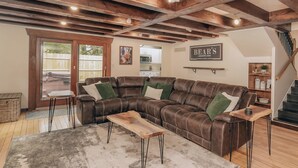 A spacious living room with a leather sectional sofa, a wooden coffee table, and a staircase leading to an upper level.