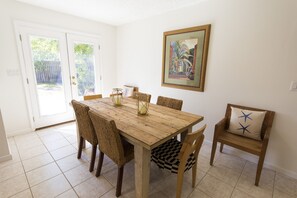 Un coin repas avec une table et des chaises en bois, un banc avec un coussin et un tableau encadré au mur.