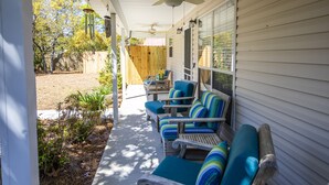 A covered porch with four wooden lounge chairs and a ceiling fan. - New to Dune Allen Realty! 10-min walk or 2-minute golf cart ride away to beach! (Santa Rosa Beach)