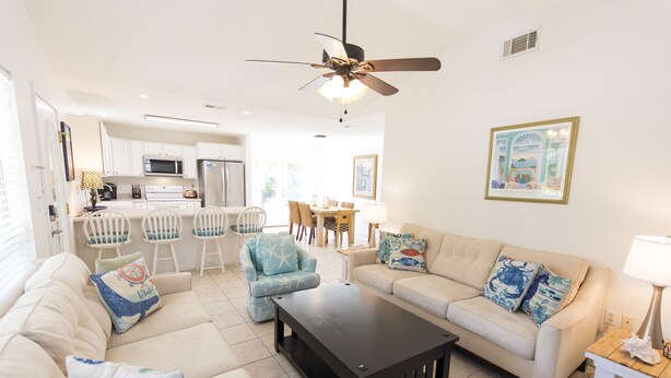 A modern living room with a sofa, armchairs, a coffee table, and a dining area with chairs and a table. - New to Dune Allen Realty! 10-min walk or 2-minute golf cart ride away to beach! (Santa Rosa Beach)