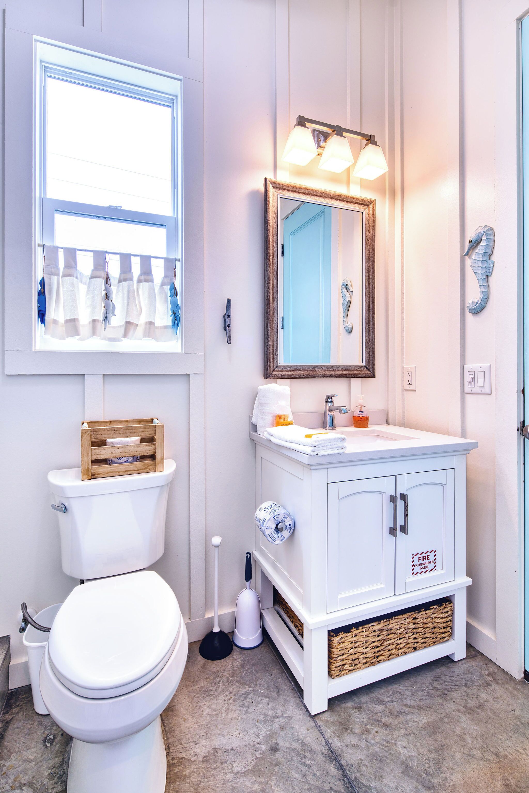 A bathroom with a toilet, sink, mirror, and window.