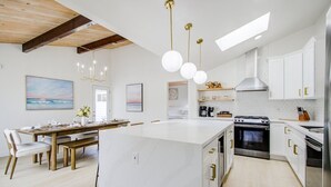 Una cocina moderna con armarios blancos, una isla central e iluminación colgante.