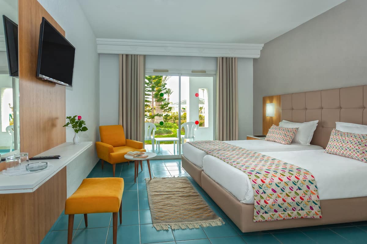 Ein Hotelzimmer mit Bett, Schreibtisch, Stuhl, Fernseher und Blick ins Freie.