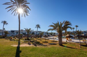 Un resort con palmeras, sombrillas de sol y una zona de piscina.