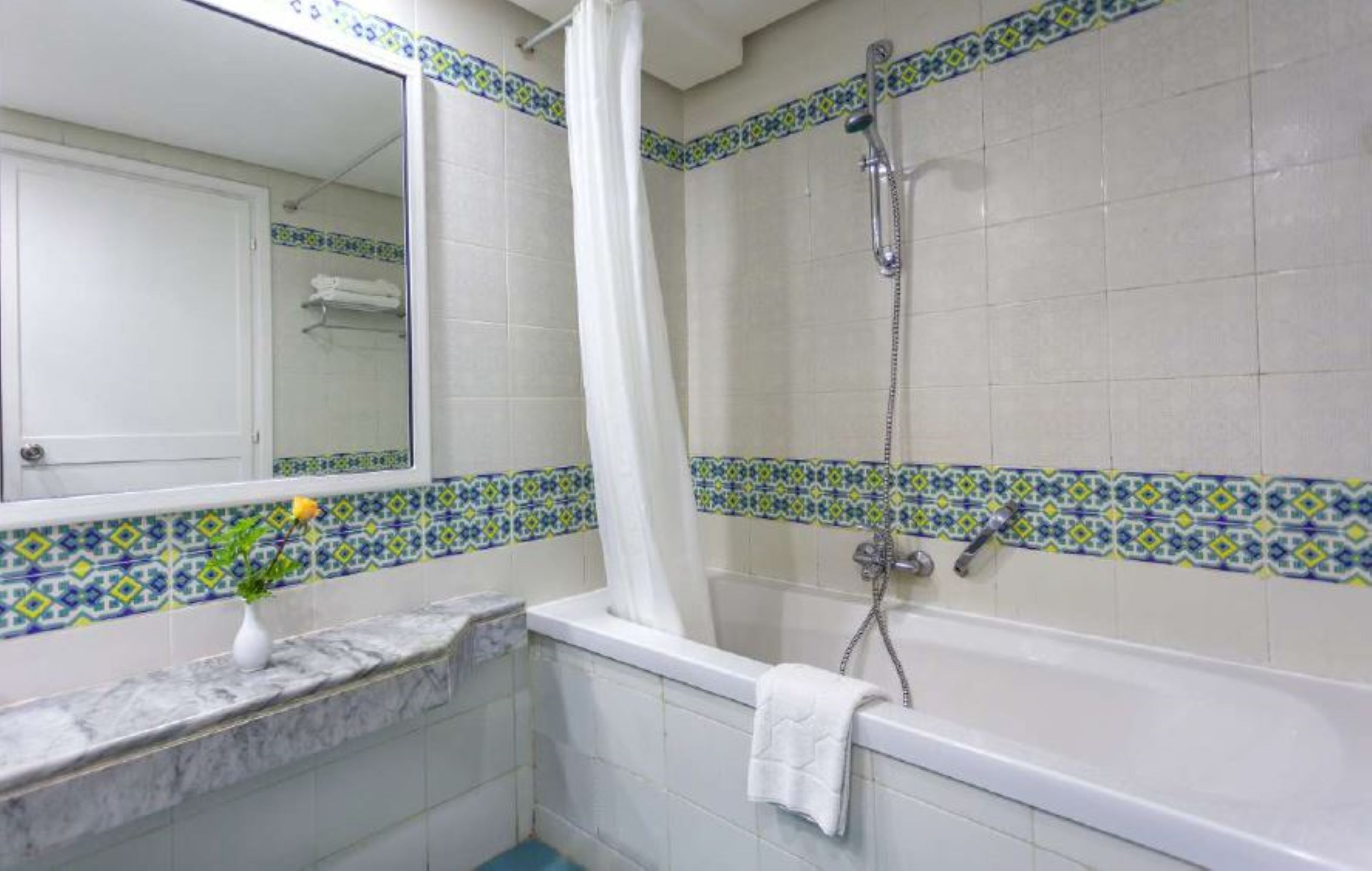 Een badkamer met een bad, douche en een spiegel.