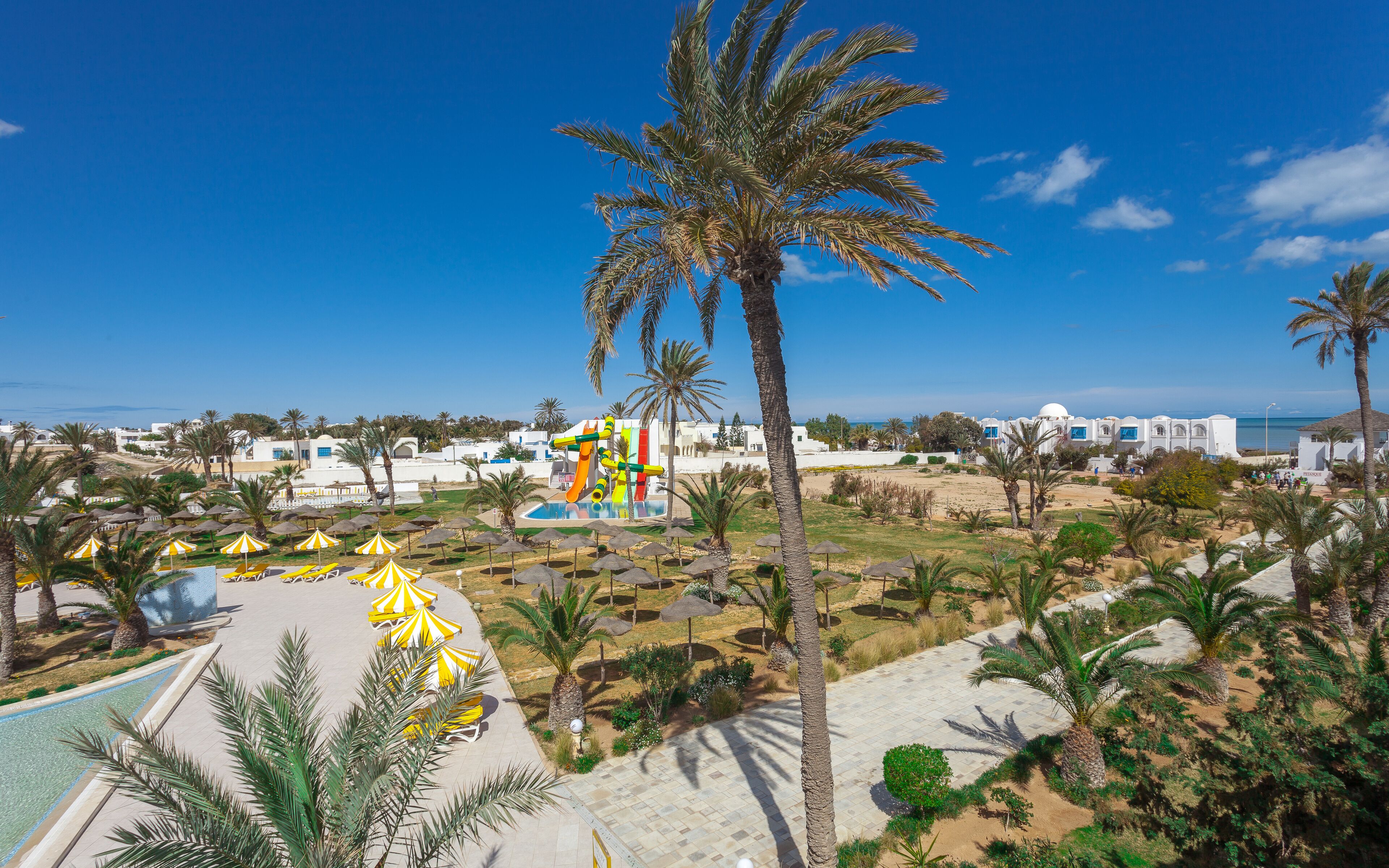 Een resort met een zwembad, palmbomen en een glijbaan.