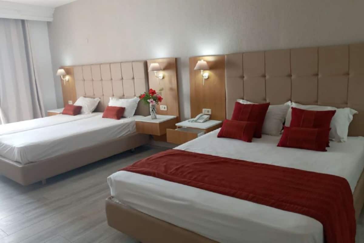Ein Hotelzimmer mit zwei Betten, jeweils mit Kopfteil, Nachttischen und Lampen.