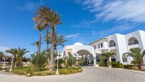 A hotel with a central courtyard, palm trees, and white architecture with arches and domes.