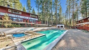 Une piscine avec un bâtiment rouge en arrière-plan, entouré d’arbres.