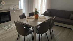 Une cuisine moderne dotée d’un four encastré, d’une table à manger avec quatre chaises et d’une plante en pot.