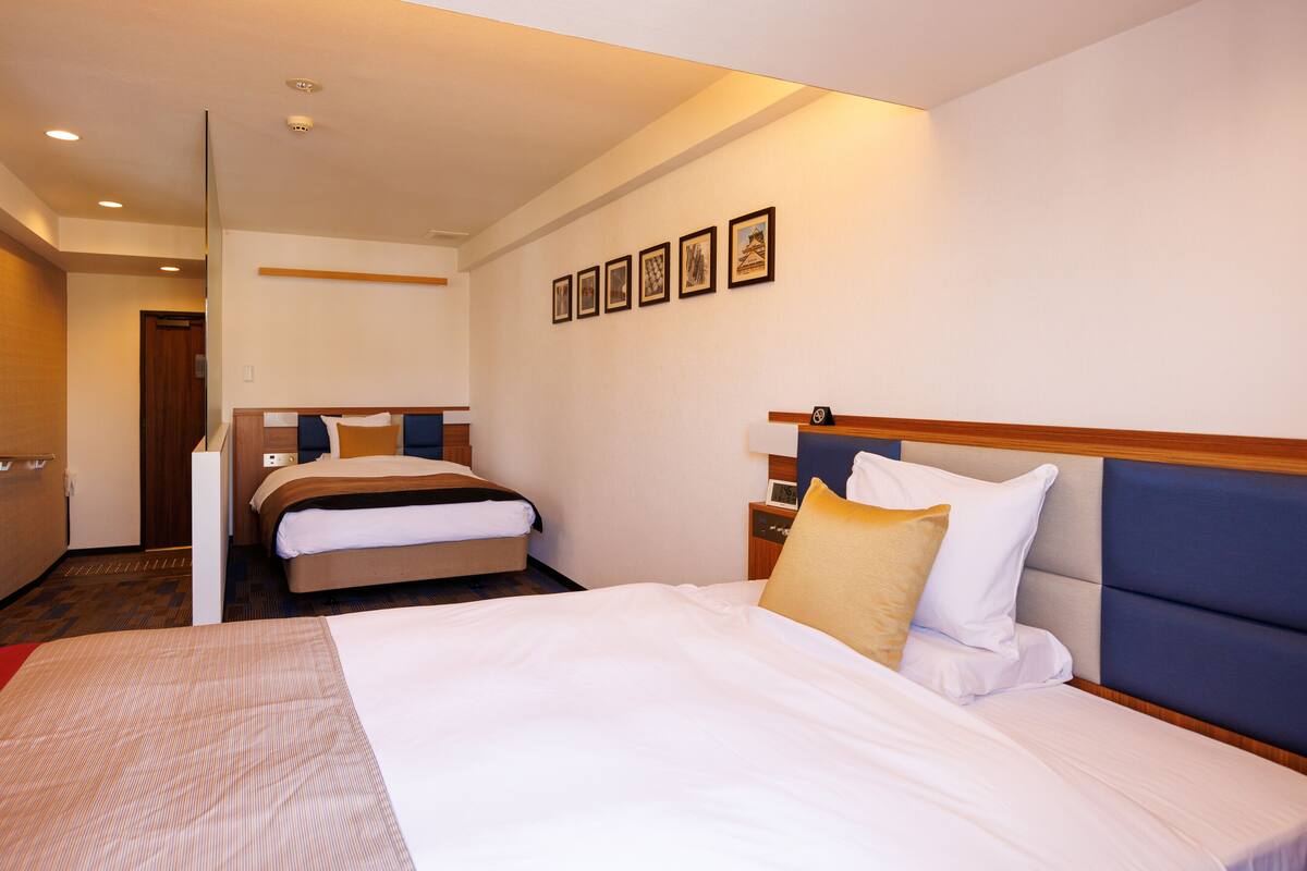A hotel room with a large bed, a smaller bed, a nightstand, and a wall with framed pictures.