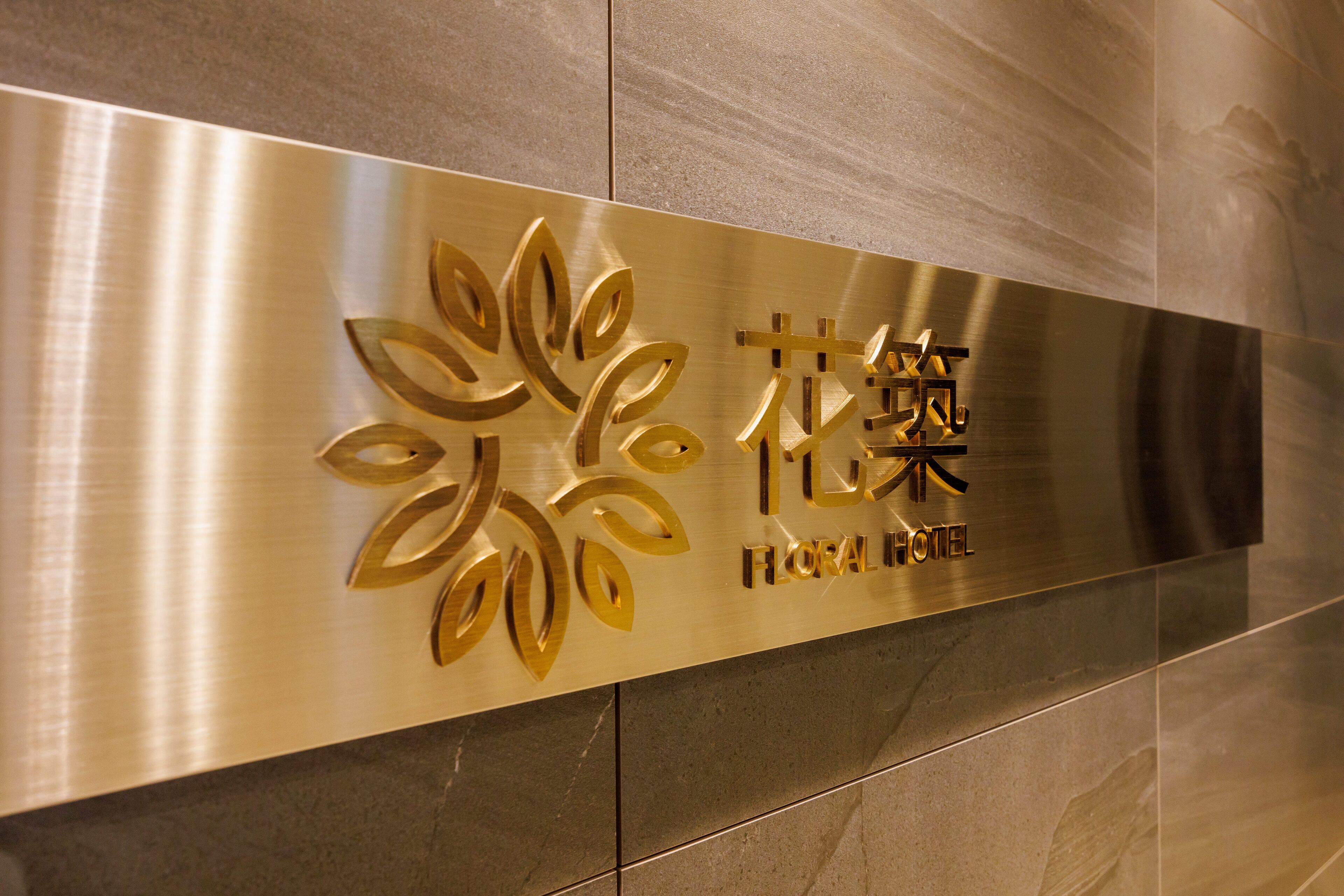 A metallic sign with stylized floral designs and the name "Floral Hotel" in both English and another script.