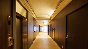 A hotel hallway with elevators, doors, and a tiled floor. - Floral Higashishinsaibashi Hotel (Osaka)