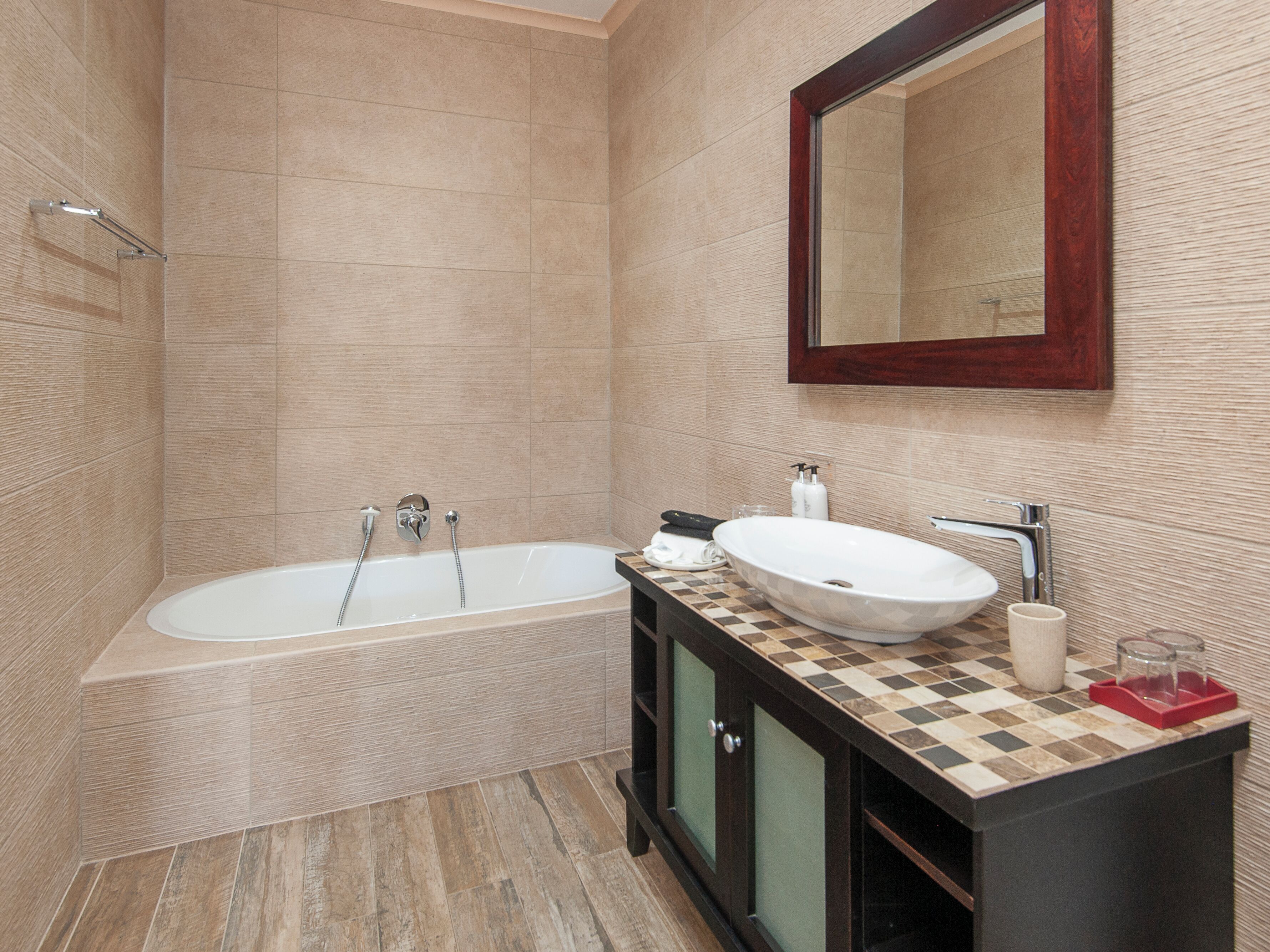 A modern bathroom with a freestanding bathtub, a large mirror, and a vanity with a checkered countertop.