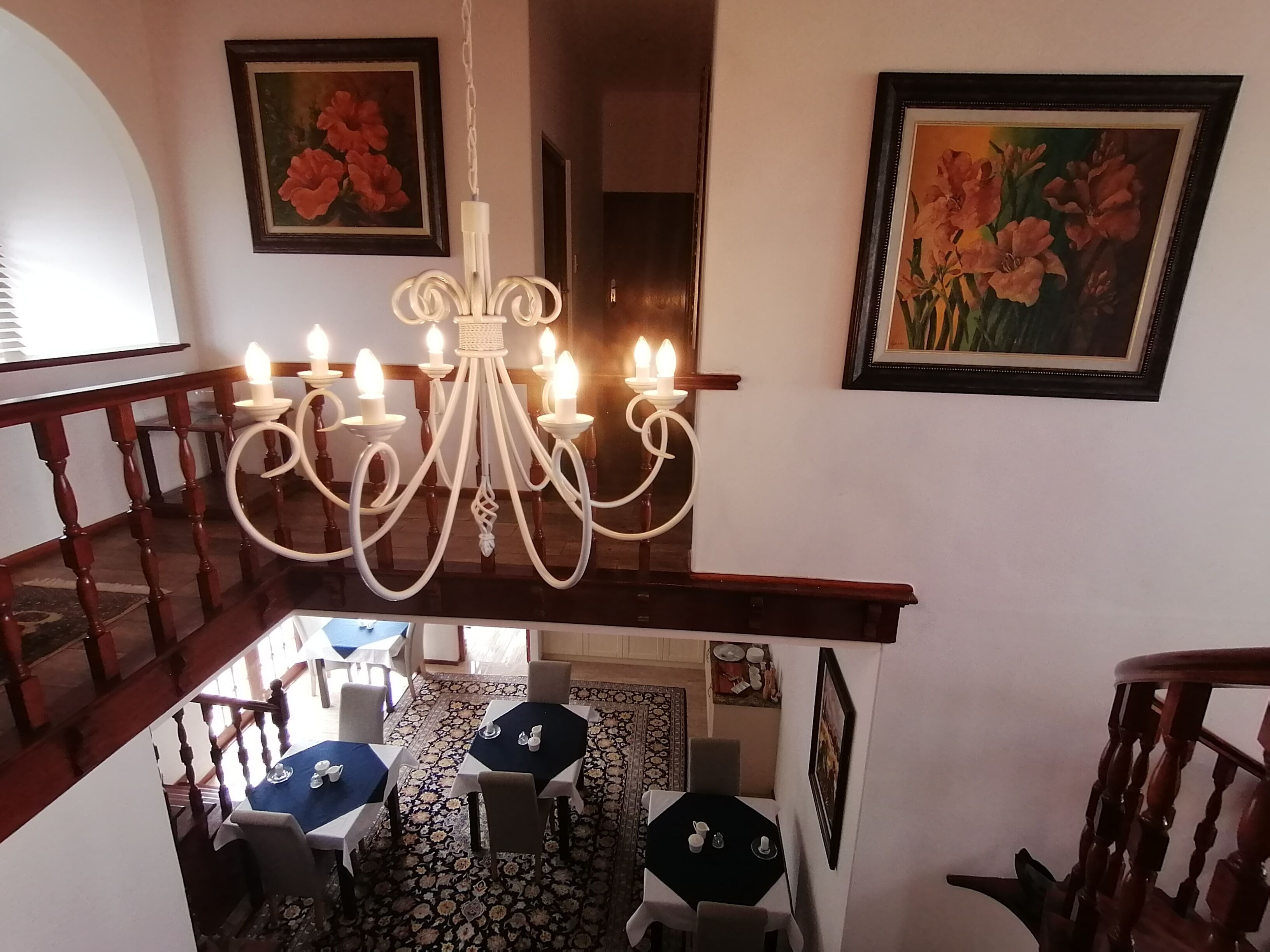Un'area pranzo con un lampadario, due quadri e una scala.