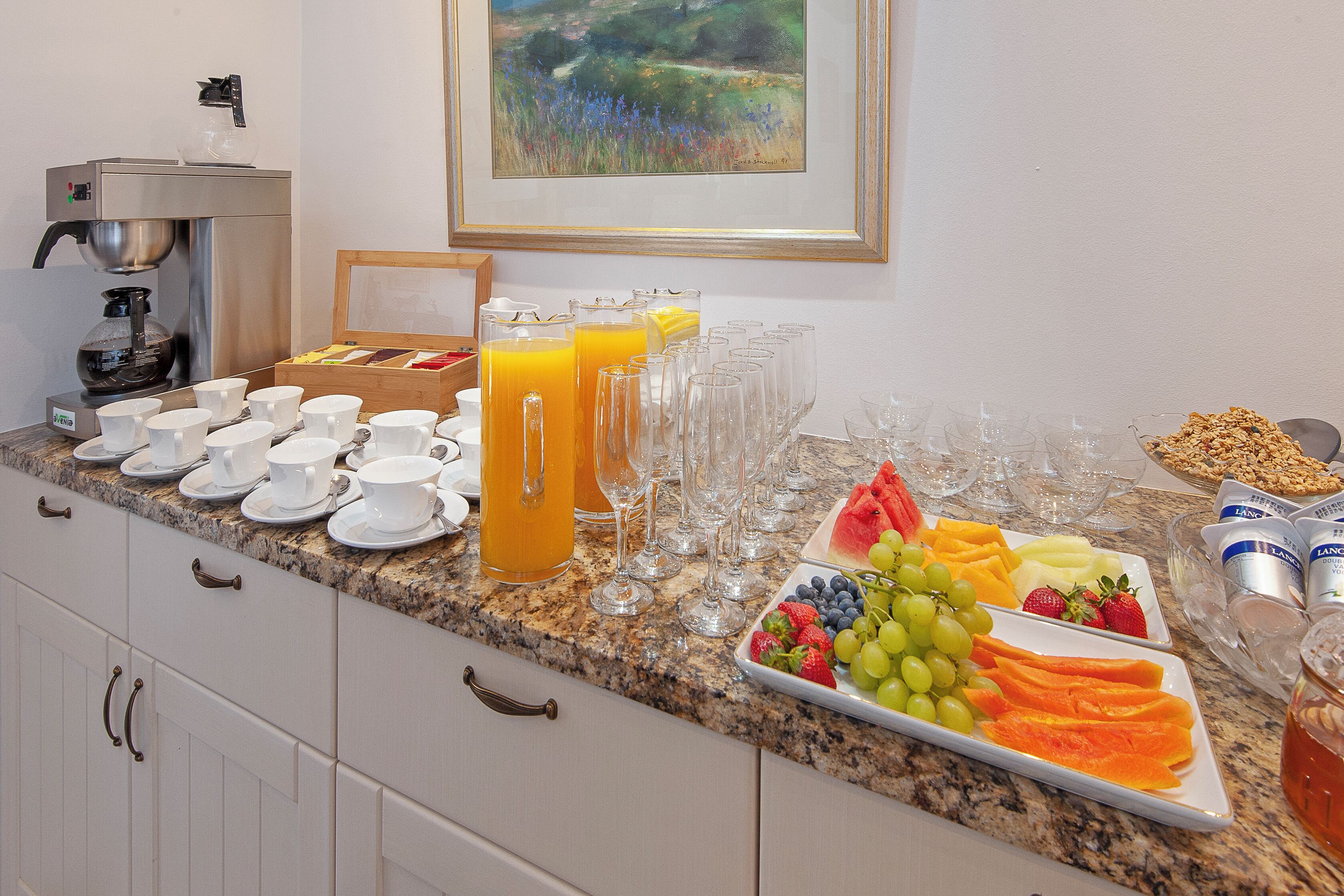 A breakfast buffet with various fruits, juices, and coffee options.